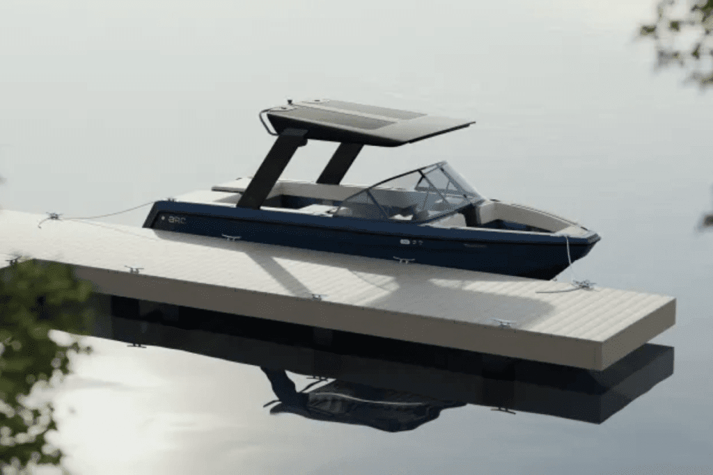 A blue and white electric boat is docked at a wooden dock on a lake.